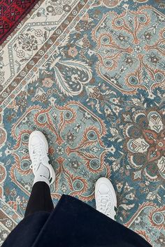 a person standing on top of a rug next to a red and blue area rug