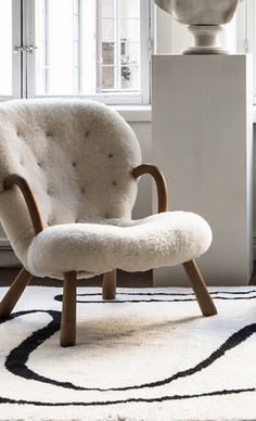 a white chair sitting on top of a rug next to a window