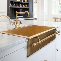 a kitchen with marble counter tops and gold faucets on the sink's side