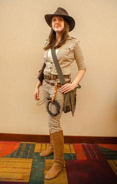 a woman dressed up as indiana jones from indiana jones is standing in front of a wall