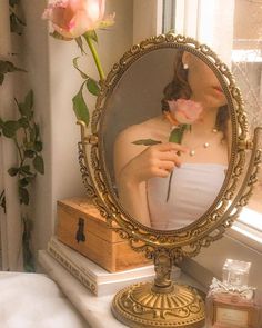 a woman is looking into a mirror with flowers in front of her and on the other side