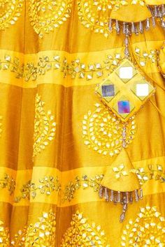 Mustard lehenga highlighted with mirror-thread embroidery and drawstring with tassels at the waist. Comes with corset-style blouse and dupatta.
Components:3
Embroidered
Neckline: V-Neck
Sleeve Length:Sleeveless
Fabric:Dupion Silk
Color:Yellow
Embroidered blouse
Beaded tassels at the hem
Closure: 
Blouse: Hooks at the back
Lehenga: Drawstring with tassels at the waist
Note: The fabric is silk blend and not pure silk - Aza Fashions Floor-length Gota Work Set For Festivals, Floor-length Festival Set With Gota Work, Festival Saree Sets With Cutdana, Navratri Chandbali Palazzo Set With Mirror Work, Festival Reception Sets With Zari Work, Festival Cutdana Dresses, Designer Mirror Work Dupatta For Festivals, Designer Festival Dupatta With Mirror Work, Traditional Drape Palazzo Set With Mirror Work For Festivals