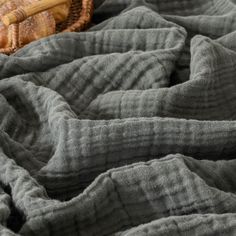 a basket sitting on top of a gray blanket next to a wooden spoon and napkin