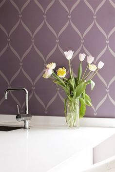 a vase filled with white flowers sitting on top of a counter next to a faucet