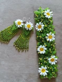 a pair of green and white earrings with daisies attached to the back of them