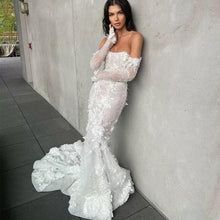 a woman in a white dress leaning against a wall with her hand on her face