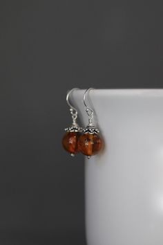 "Gorgeous round Baltic Amber beads are wire wrapped with balled silver pins and topped with Bali Silver caps. These dangle from balled silver earwires. These interesting natural stones feature colors in various shades of orange. Perfect everyday earrings. Each pair of beads will vary. Baltic Amber beads: 10mm Total length of earrings: 1 1/8\" All silver is sterling. As the owner, maker, designer, and curator of this shop, I take great pride in providing you with jewelry that you will love to wea Earrings Bali, Bali Silver, Silver Caps, Amber Earrings, Jewelry Beaded, Amber Beads, Silver Pin, Earrings Statement, Everyday Earrings