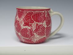 a red and white coffee cup with strawberries on it