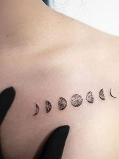 a woman's chest with six phases of the moon tattoo on her left side