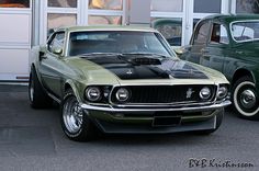 two classic muscle cars parked in front of a building