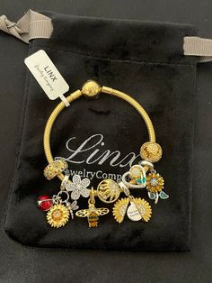 a gold bracelet with charms on it sitting in a black velvet bag next to a name tag