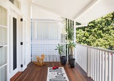 a porch with wooden flooring and white fenced in area next to potted plants