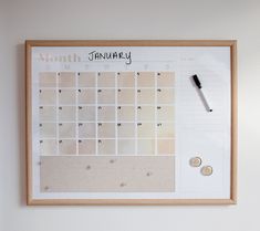 a wooden frame with a calendar on it and a pen resting on the wall next to it