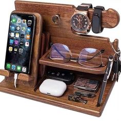 an iphone, watch and glasses are in a wooden holder with cell phones on it