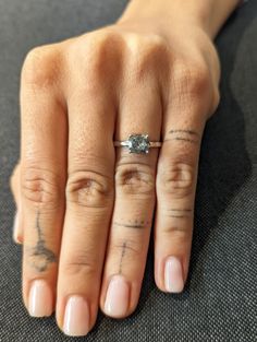 a woman's hand with tattoos and a ring on her left thumb, resting on the floor