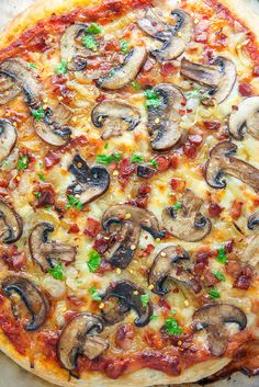 a pizza with mushrooms on it sitting next to a knife and fork