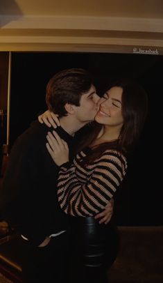 a man and woman kissing each other in front of a mirror