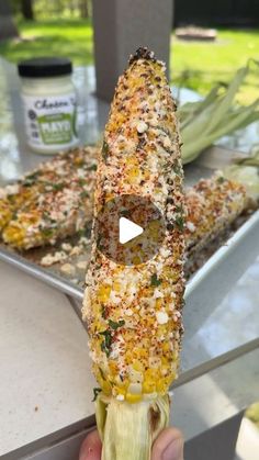 someone is holding up a corn on the cob with seasoning in front of them