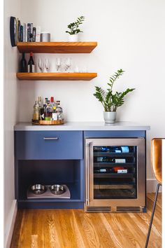 a kitchen with blue cabinets and shelves filled with bottles, wine glasses, and silverware