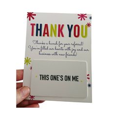 a hand holding up a thank card with the words, thank you and one's on me