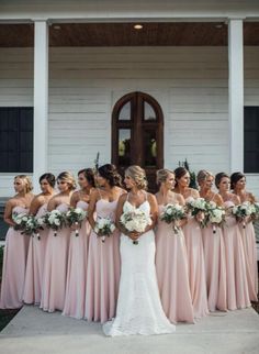 a group of women standing in front of a white building with flowers on their heads