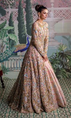 a woman standing in front of a peacock wallpaper