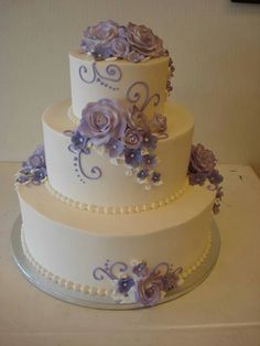 a three tiered wedding cake with purple flowers