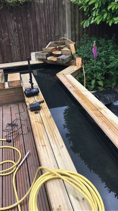 a small boat is sitting in the water next to a wooden dock and garden hoses