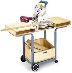 a table sawing machine on top of a wooden cart with two drawers underneath it