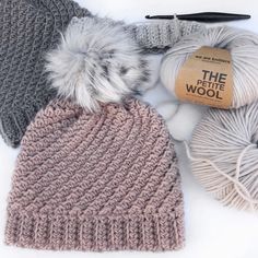 three balls of yarn, one with a ball of knitting needles and the other with a crochet hat