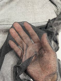 a person's hand holding onto a piece of mesh on top of a shirt