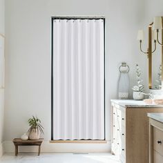 a white shower curtain in a bathroom next to a sink and vanity with a potted plant on the counter