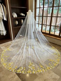 a white wedding veil with yellow flowers on the floor