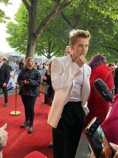 a man in white jacket and black pants on red carpet