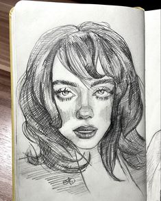 a pencil drawing of a woman's face with long hair and eyes, in an open book