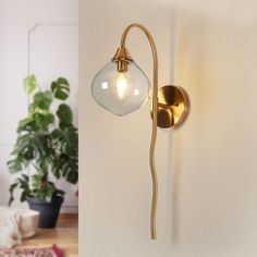 an image of a wall light that is on the wall and next to a potted plant