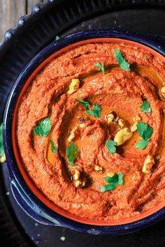 a black plate topped with an orange hummus