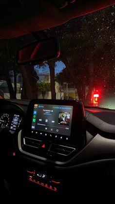 the interior of a car with an entertainment system in the center and red lights at night