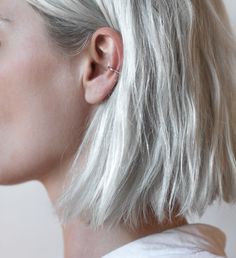 a woman with blonde hair and piercings on her ear looking off to the side