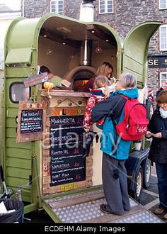 some people are standing in front of a food truck that is open to the public