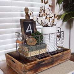 a wooden tray with a sign and some plants in it on top of a table