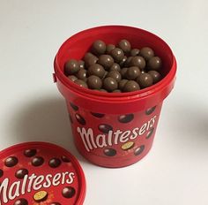 two red containers filled with chocolate candies on top of a white table next to each other