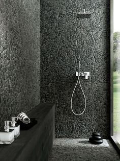 a black and white photo of a bathroom with a shower head, soaps and glasses on the counter