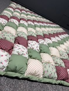 a patchwork quilt with many different colored pillows on the bottom, and polka dot cushions on the top