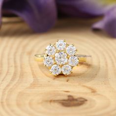 a diamond cluster ring sitting on top of a wooden table