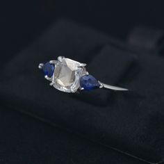 an engagement ring with two blue sapphire stones on the side and a white diamond in the middle