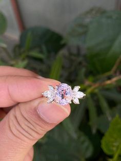 a person holding a ring in their left hand with flowers on the top and bottom