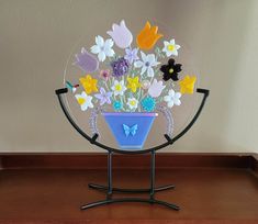 a glass plate with flowers and butterflies in it on a metal stand next to a wall