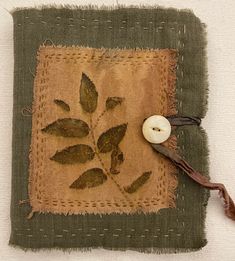 a piece of cloth with a button on it and some leaves in the middle,