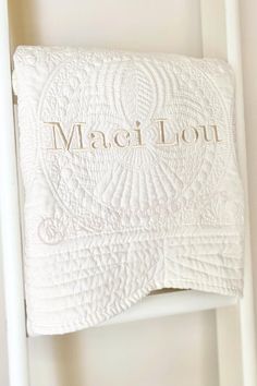 a white ladder with a towel hanging on it's side and the word, magi lout written in gold